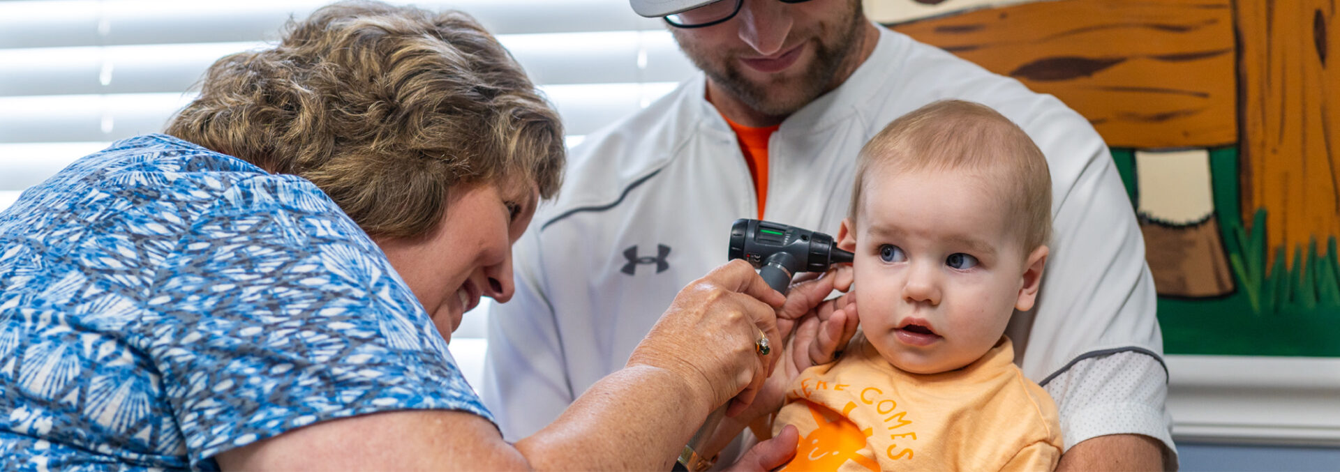 a baby being examined by an adult in front of a window