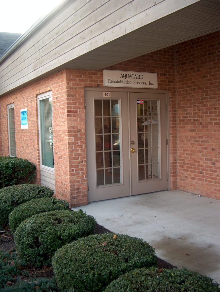 the front entrance of a building with several bushes