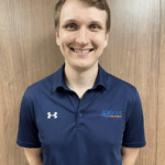 a man standing in front of a wooden wall