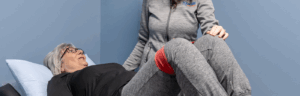 a woman sitting on top of a bed next to a physical therapist