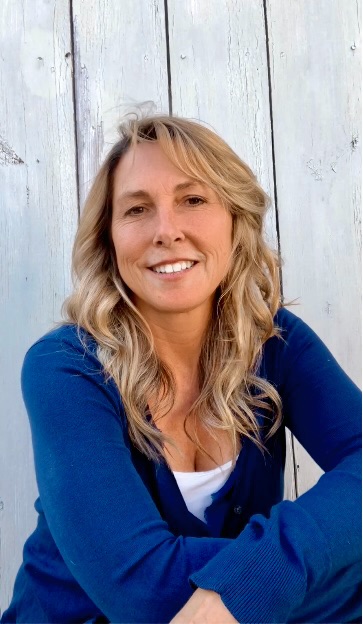 a woman with blonde hair sitting in front of a wooden wall