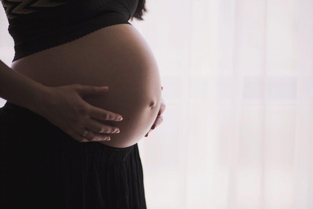 a pregnant woman in a black dress holding her belly