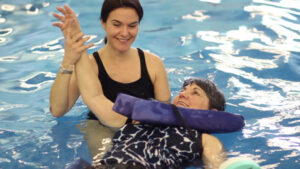 two women in a swimming pool one is holding the other's hand