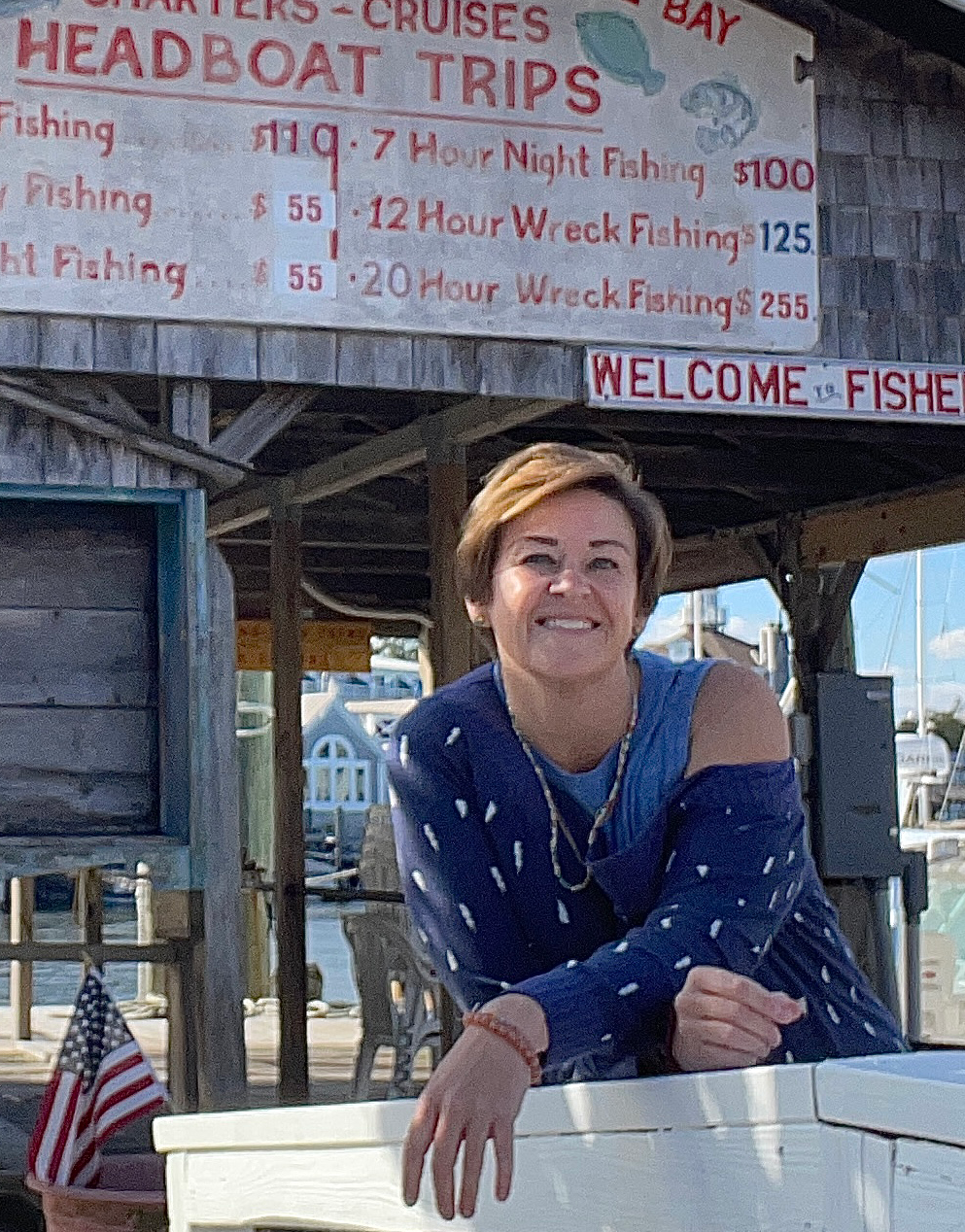 a woman leaning on a white surfboard in front of a sign