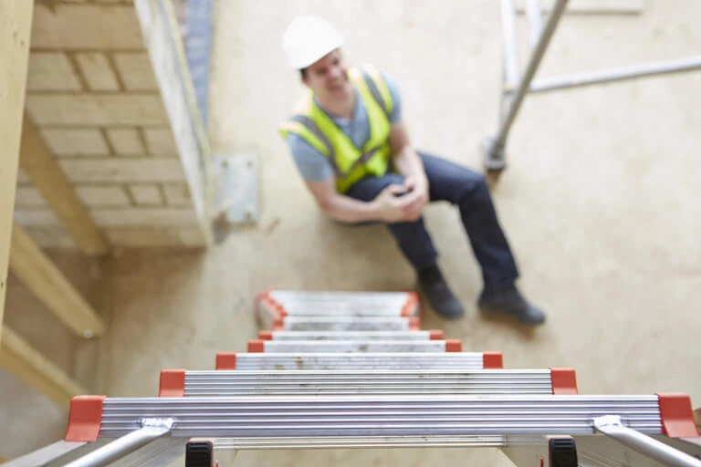 a man in a safety vest sitting on a ladder