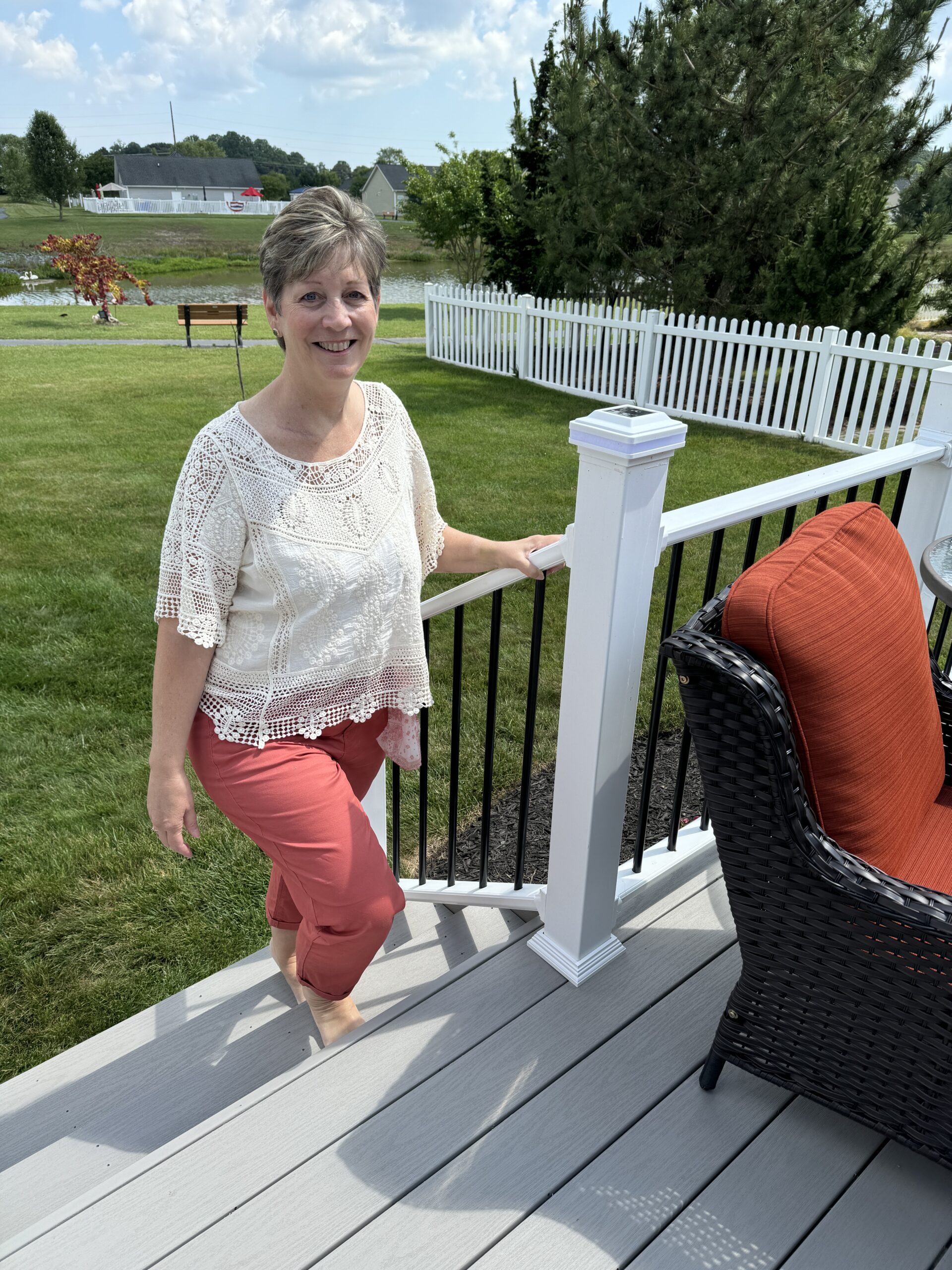a woman standing on a porch next to a chair
