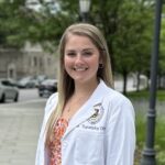 a woman in a lab coat standing on a sidewalk