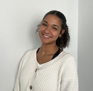 a smiling woman leaning against a white wall