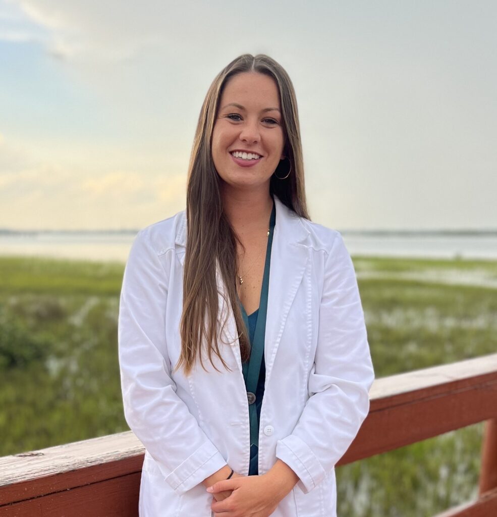 a woman in a white lab coat standing on a boardwalk