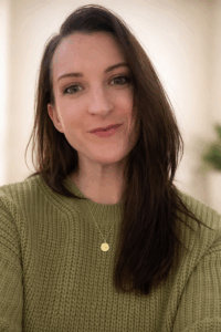 a woman in a green sweater is looking at the camera