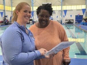 two women standing next to each other in front of a swimming pool