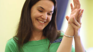 a woman in a green shirt holding her hand up