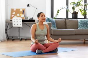 a woman sitting on a yoga mat in a living room