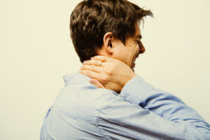 a man in a blue shirt is holding his neck