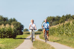 two people riding bikes down a path in the grass