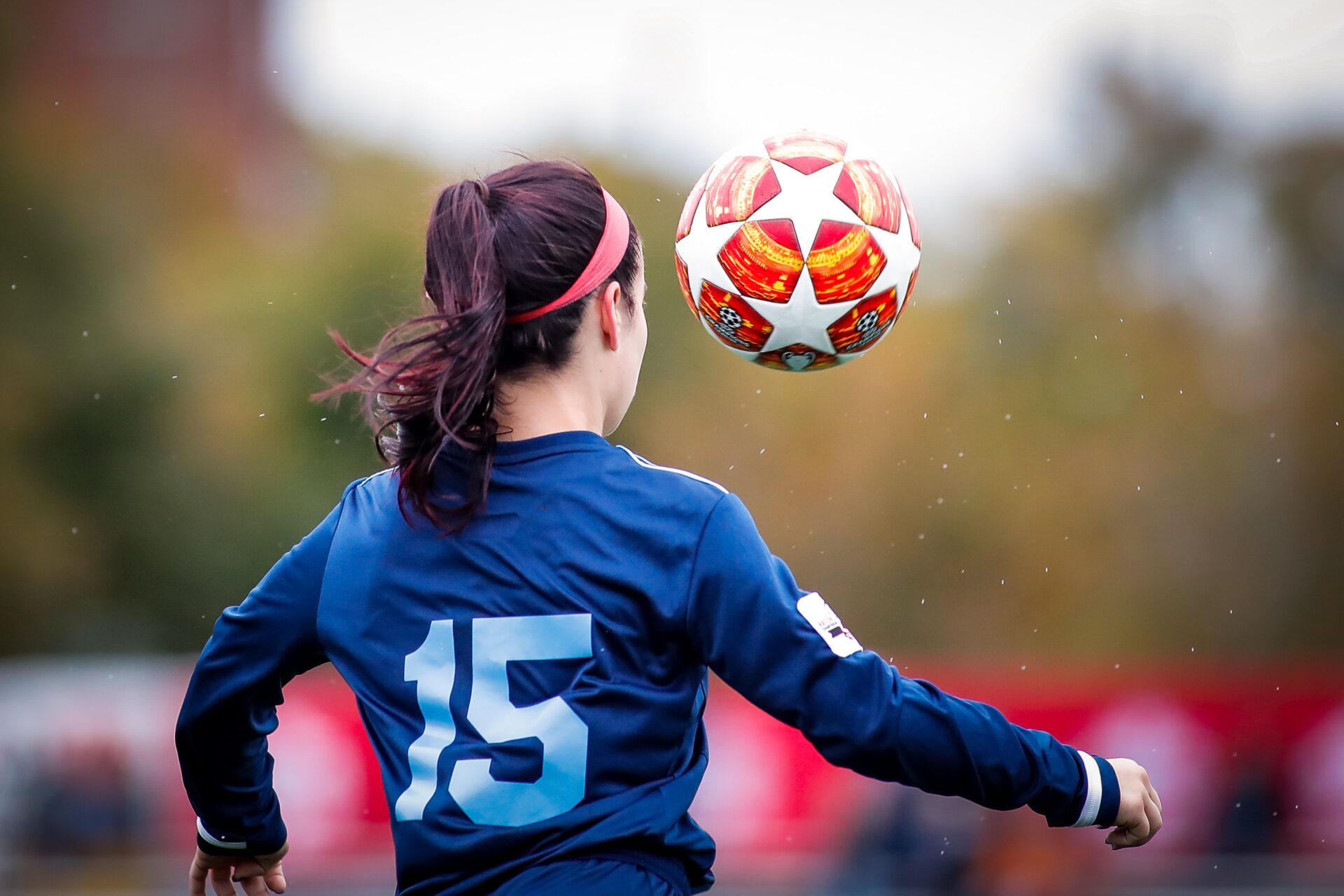 a woman in a blue shirt is playing soccer