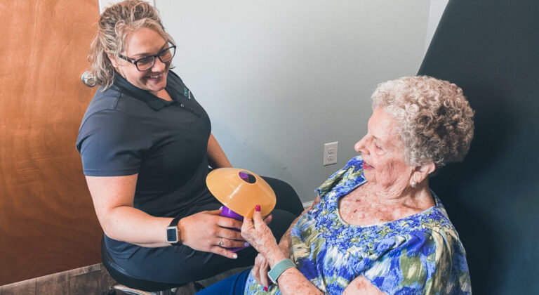an older woman holding a yellow frisbee next to a younger woman