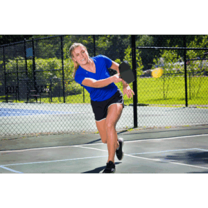 a woman in blue shirt and black shorts playing pickleball