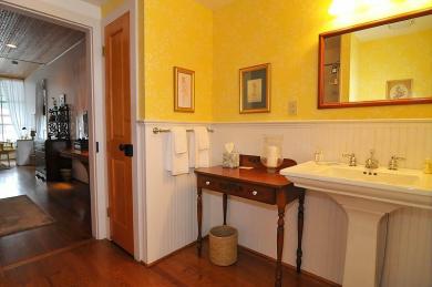 The Gardner’s Cottage Bathroom Atlantic Hotel hotel guest room bathroom with hardwood floors baseboard paneling sink table and mirror with yellow painted walls