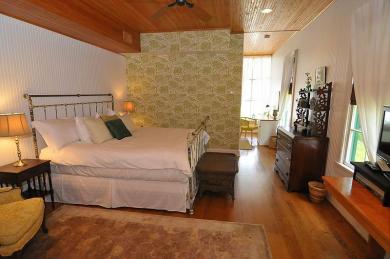 The Gardner’s Cottage Bedroom with View of Sitting Area Atlantic Hotel cottage bedroom with iron bed and white comforter dresser and view of seating area