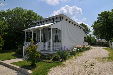 The Gardner’s Cottage Backyard Atlantic Hotel small white cottage with front porch and flowers on the side on a sunny day