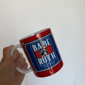 A hand holding the babe ruth museum mug showing the museum's logo