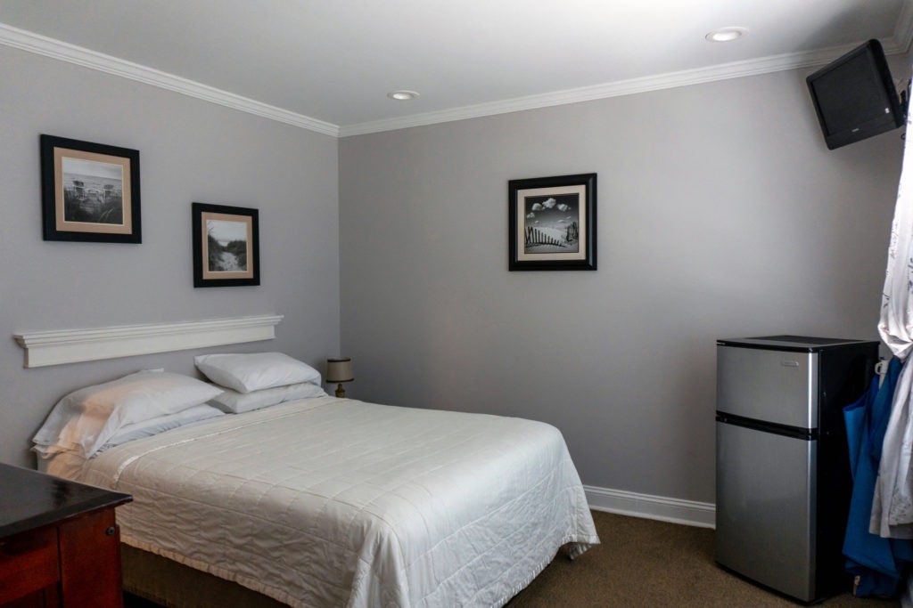 room with 1 queen bed, mounted flat screen tv, and mini fridge
