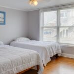 two beds next to large window in apartment