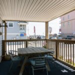covered front porch with table and chairs and view of boardwalk