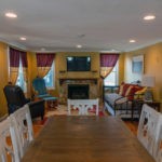 view from dining table into living room with recliners, fireplace, flat screen TV, and trundle bed