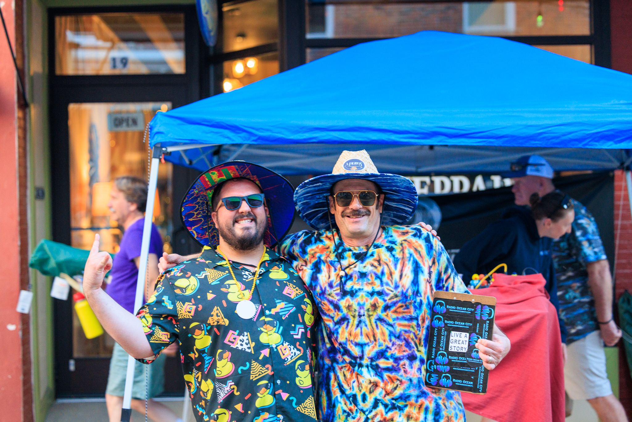 a couple of men standing next to each other under a blue tent