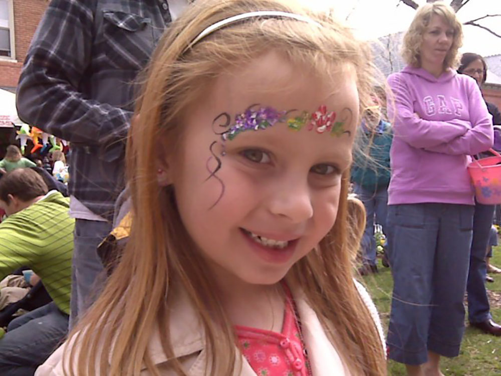 a little girl with face paint standing in front of a group of people