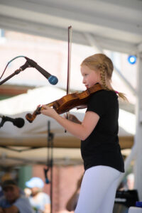 a young girl playing a violin on stage