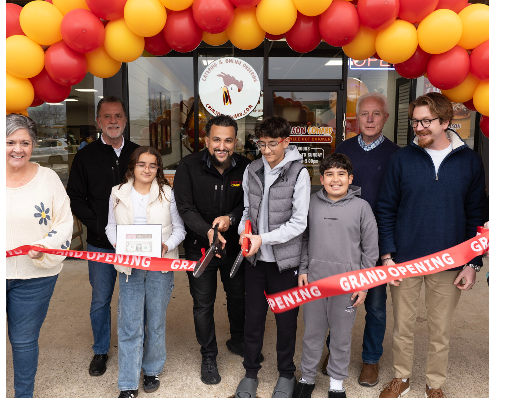 a group of people holding a ribbon in front of a building