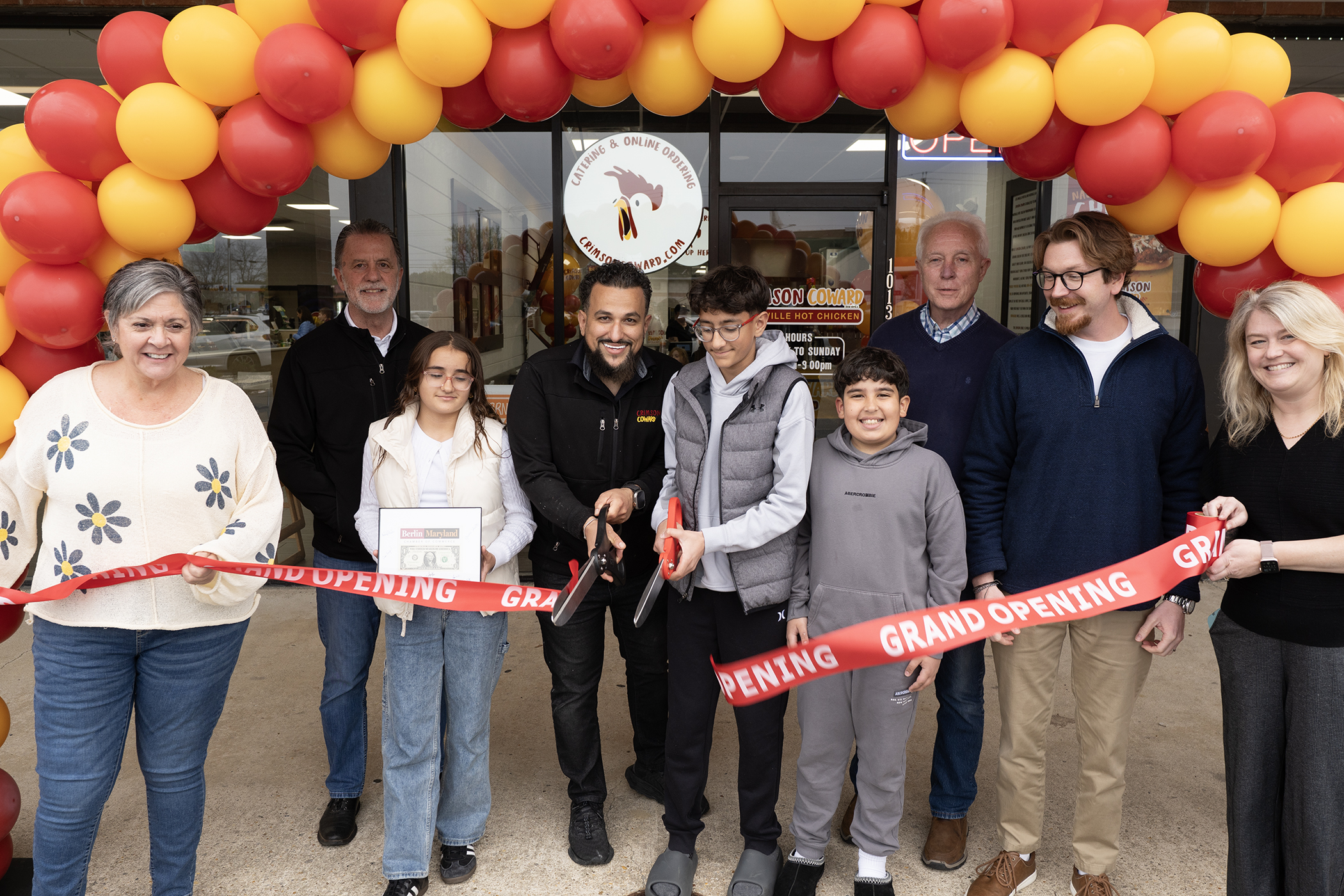 a group of people holding a ribbon at a ribbon cutting ceremony