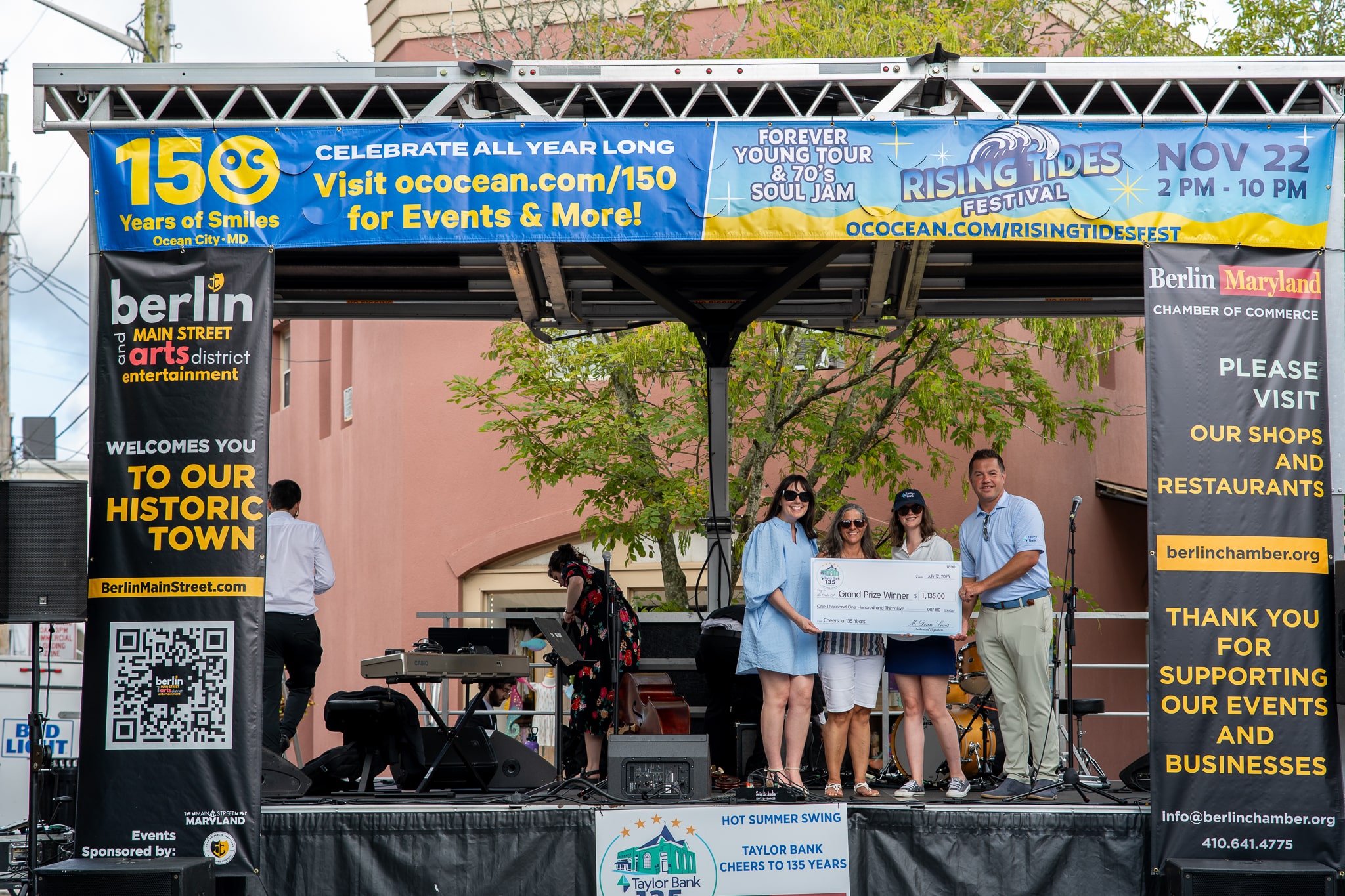 4 people holding up a big check on a stage.