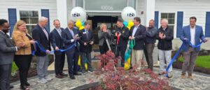 a group of people cutting a ribbon in front of a building
