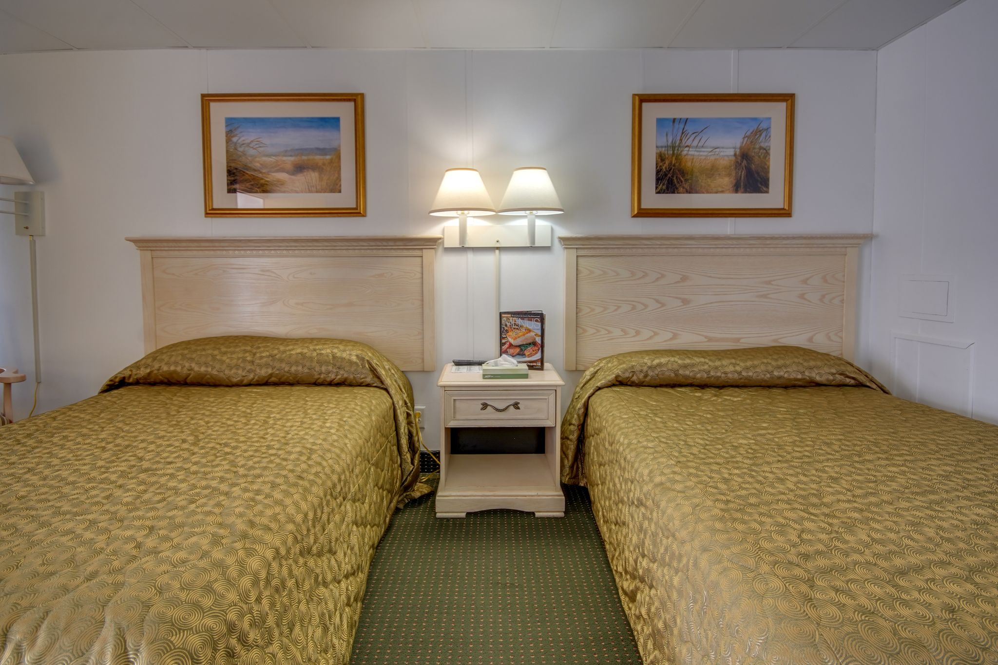 two beds in a hotel room with pictures on the wall