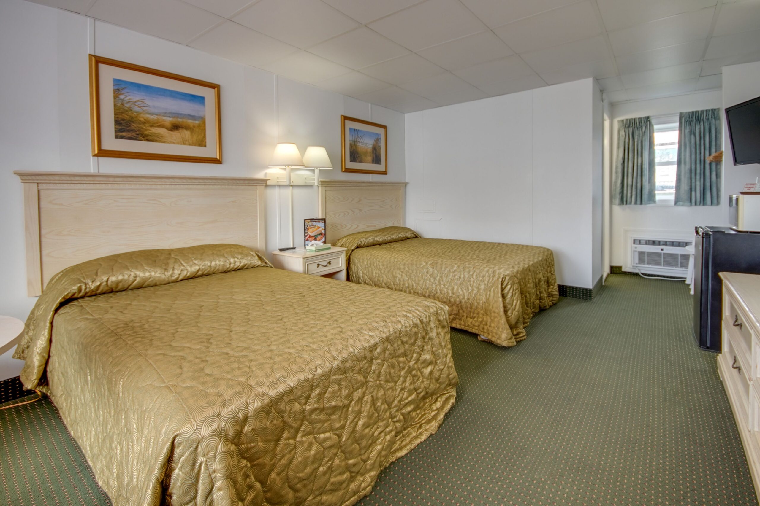 a hotel room with two beds and a flat screen tv