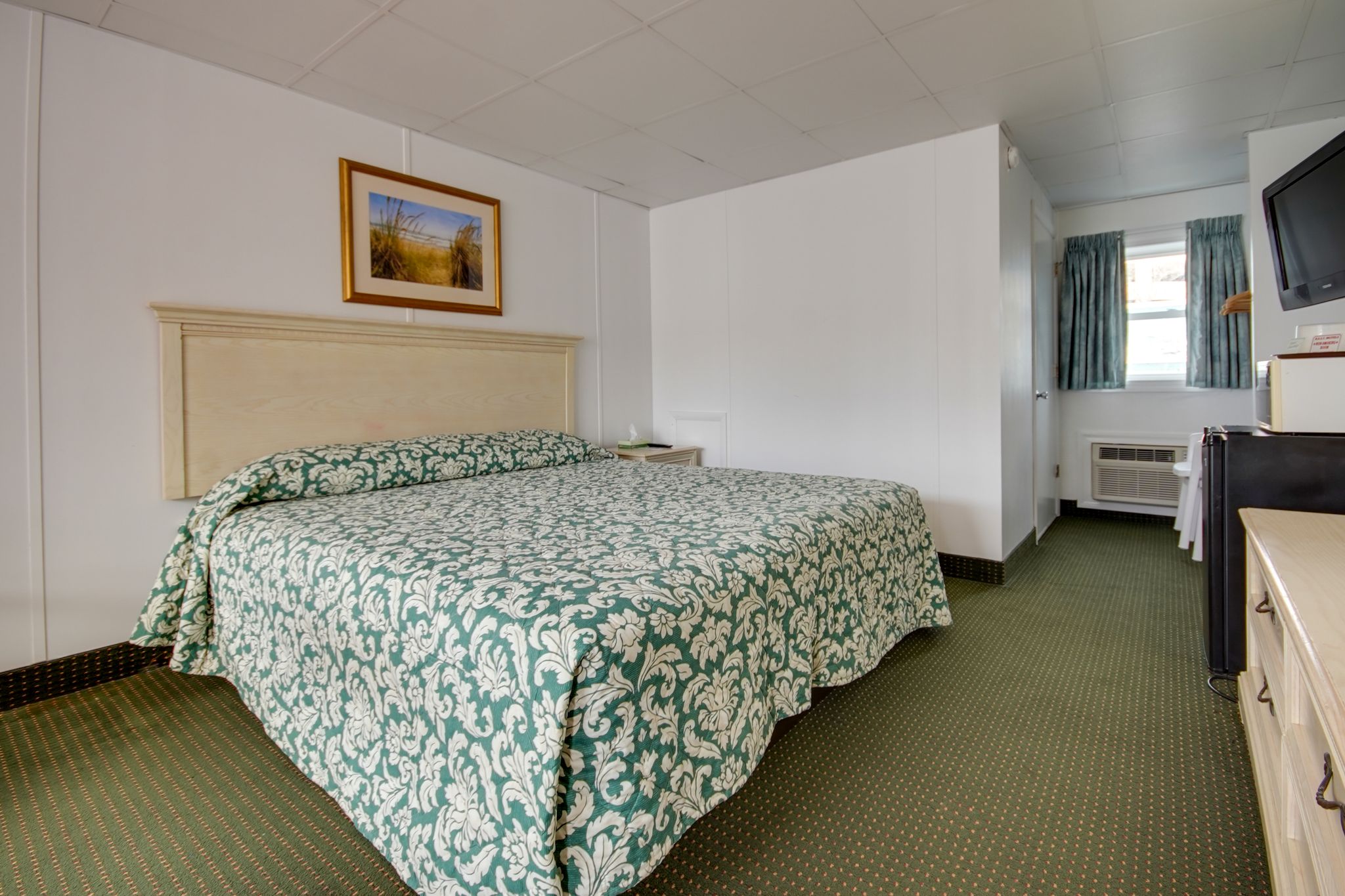 a bed room with a neatly made bed and a flat screen tv