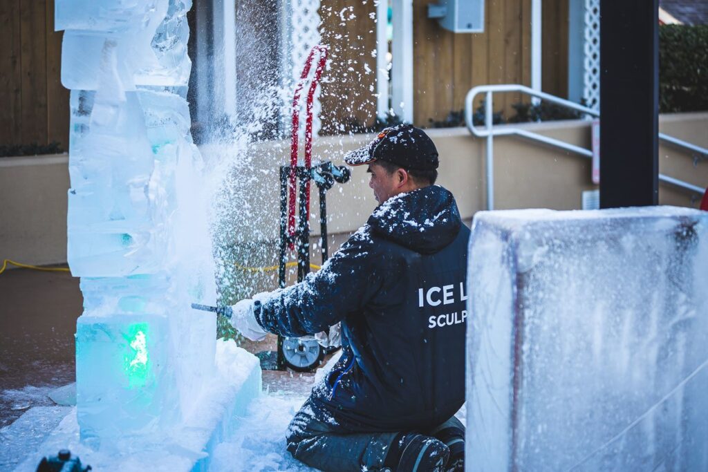 a man in a black jacket is spraying water on an ice sculpture