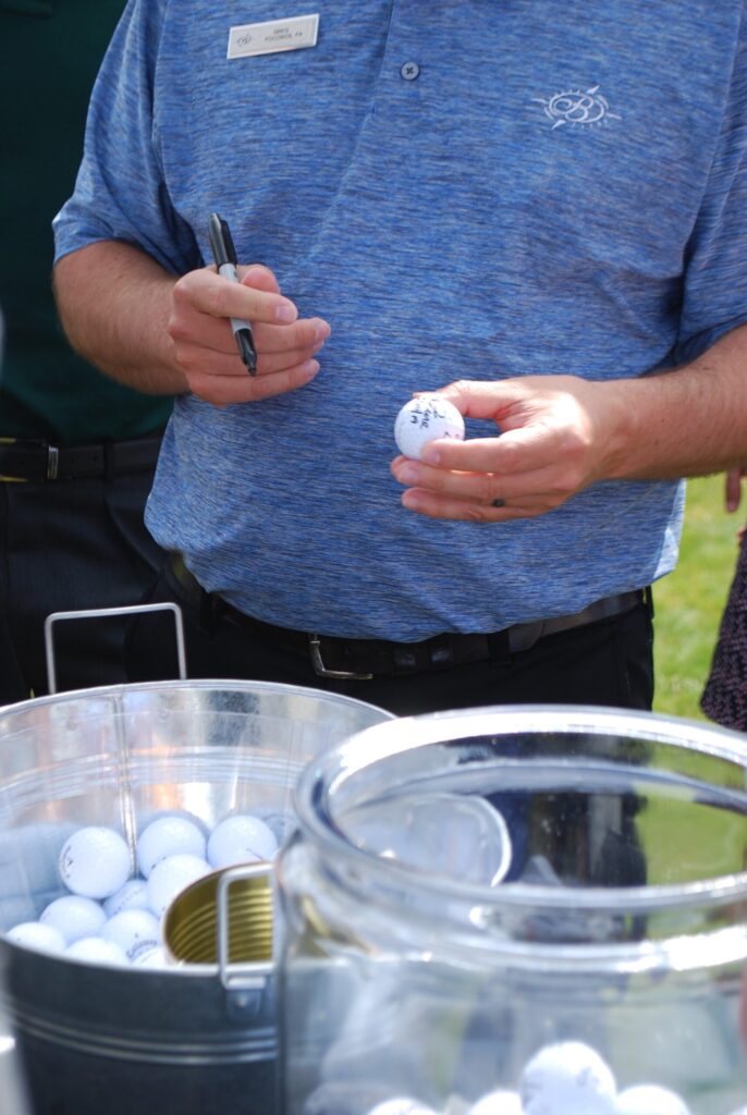 a man standing next to a table filled with golf balls