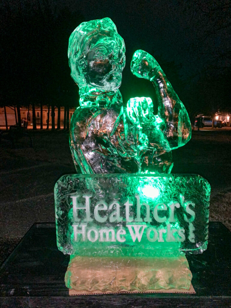 a green light up statue of a cat sitting on top of a block of ice