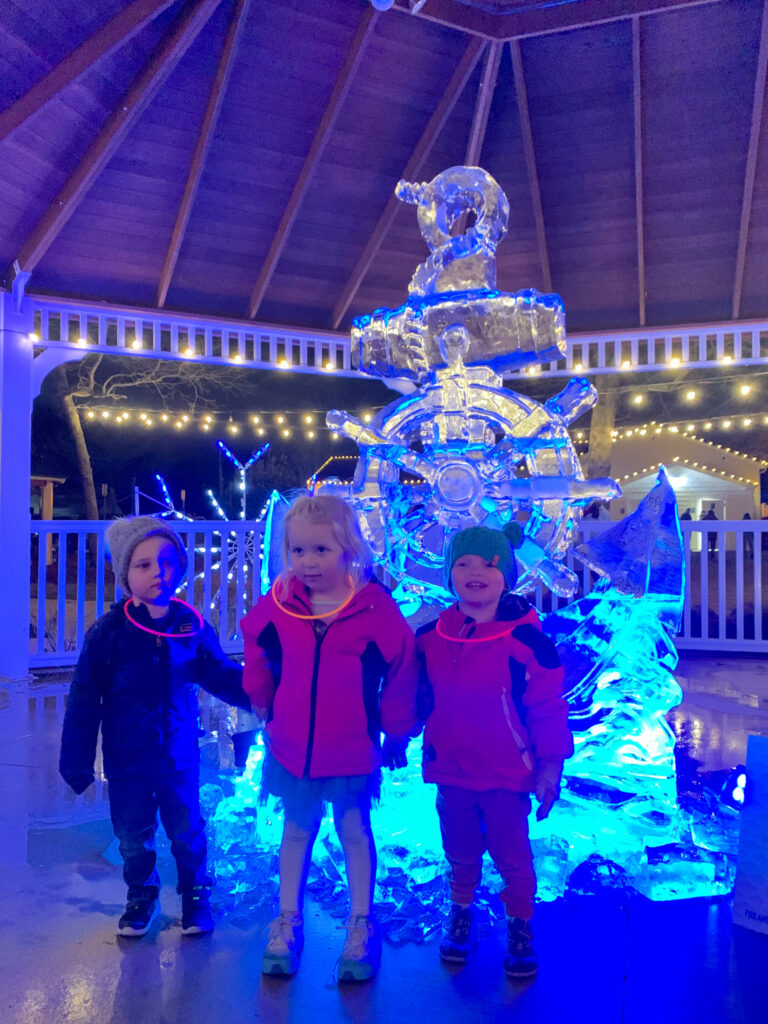 three children standing in front of a ice sculpture