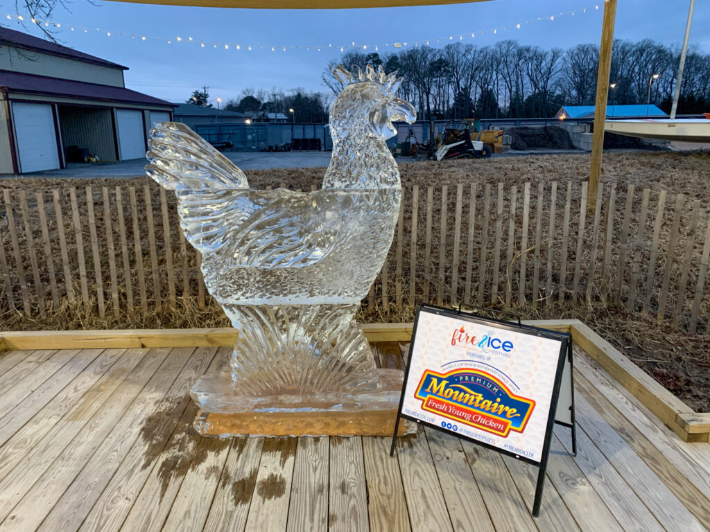 a glass chicken on a wooden deck next to a sign