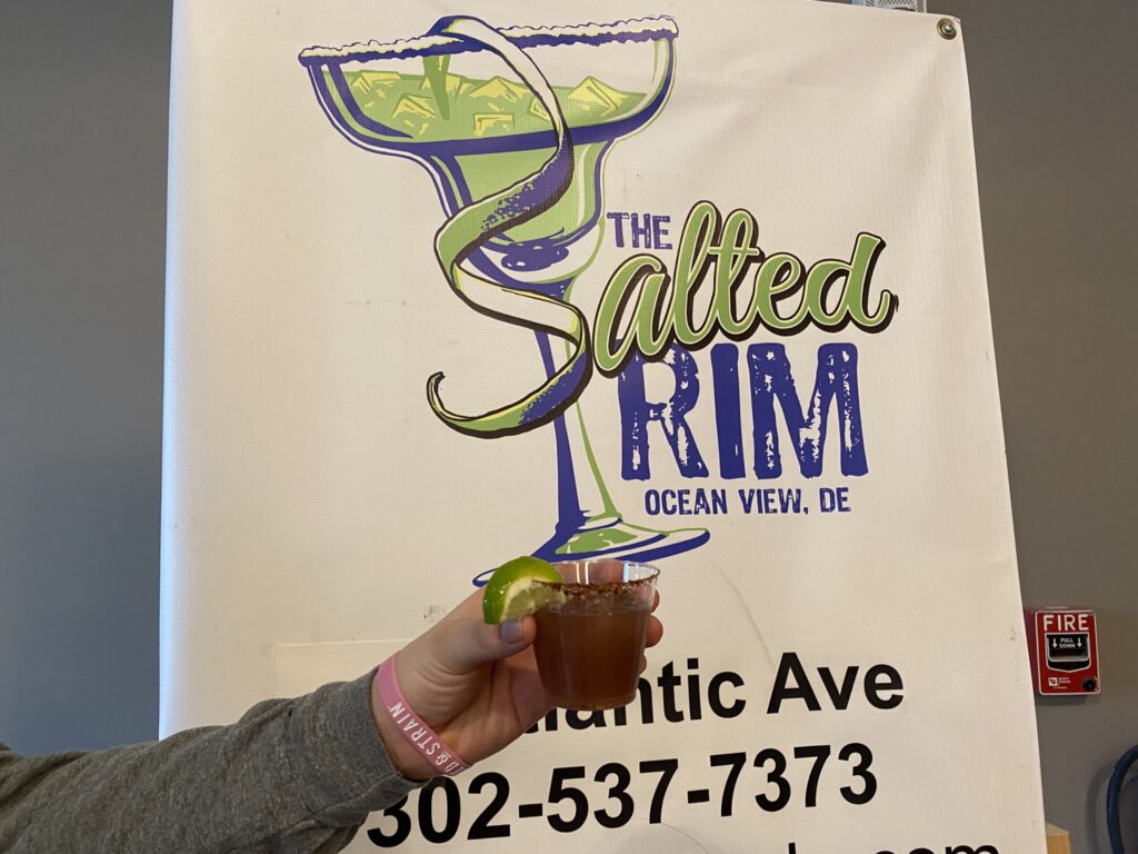 a woman holding a drink in front of a sign