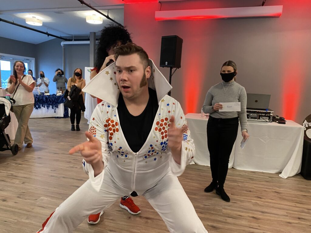 a man in a white suit is dancing on a wooden floor