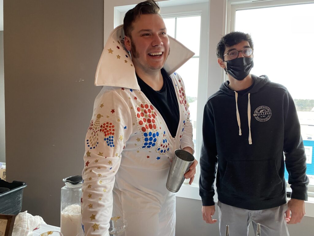 a couple of men standing next to each other in front of a window