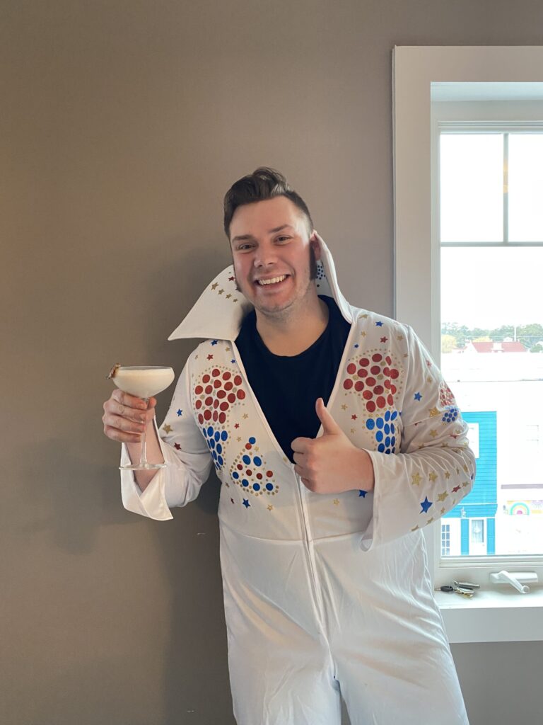 a man in a white suit holding a cup