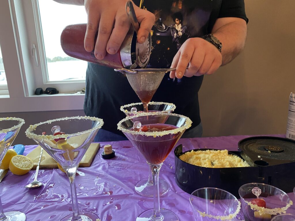 a man pouring a drink into a martini glass